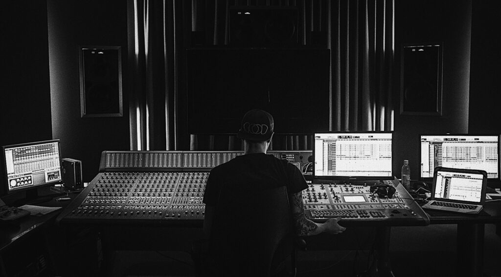 Profilepicture Sound Designer Alex Wuertz sitting on a mixing desk.